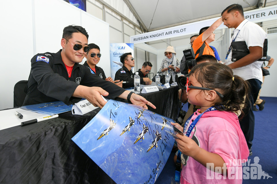 말레이시아 'LIMA '23 국제에어쇼' 퍼블릭 데이가 열린 5월 26일(금)(현지시간) 공군 특수비행팀 블랙이글스(Black Eagles) 5번기 조종사 정한울 대위가 사인회를 찾은 현지 관람객 어린이와 소통하고 있다. (사진:공군)